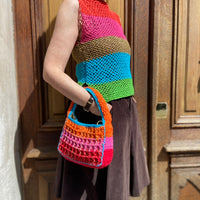 Upscale Anabaum Boxy bag in vibrant technical crochet held by a model wearing an Anabaum top at a sunny Parisian location.