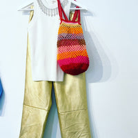 Anabaum sac fait au crochet a la main modele OG grand couleur vibe porté sur un pantalon doré avec un haut blanc