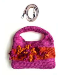 Sac à main au crochet fait main en coton rose fuchsia et violet, orné de fleurs en relief multicolores, avec poignée intégrée, sur fond blanc.

Bandoulière amovible et réglable en cuir cognac
