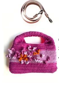Sac à main au crochet fait main en coton rose fuchsia et violet, orné de fleurs en relief multicolores, avec poignée intégrée, sur fond blanc.
Bandoulière en cuir cognac amovible et réglable.
