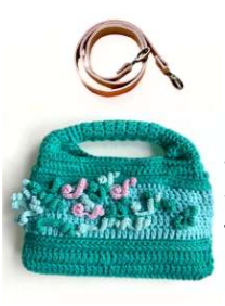 Sac à main au crochet fait main en coton vert et celadon, orné de fleurs en relief, avec poignée intégrée, sur fond blanc. Bandoulière amovible et réglable en cuir cognac.