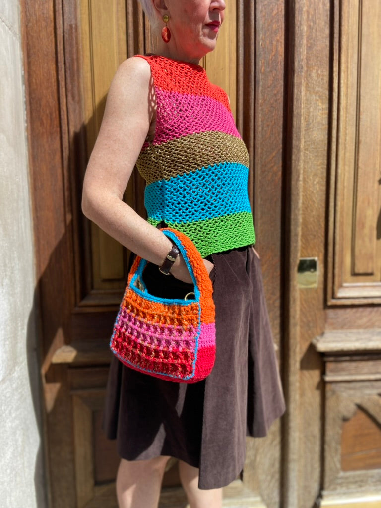 Upscale Anabaum Boxy bag in vibrant technical crochet held by a model wearing an Anabaum top at a sunny Parisian location.