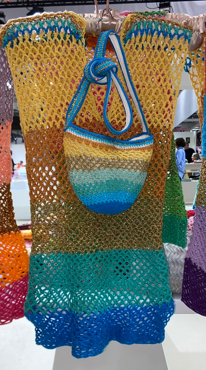 Paris Designed Handmade crochet dress and matching bag set featuring an open mesh knit and gradient colors from yellow to blue, with a striped crochet bucket bag and blue shoulder strap, displayed indoors.