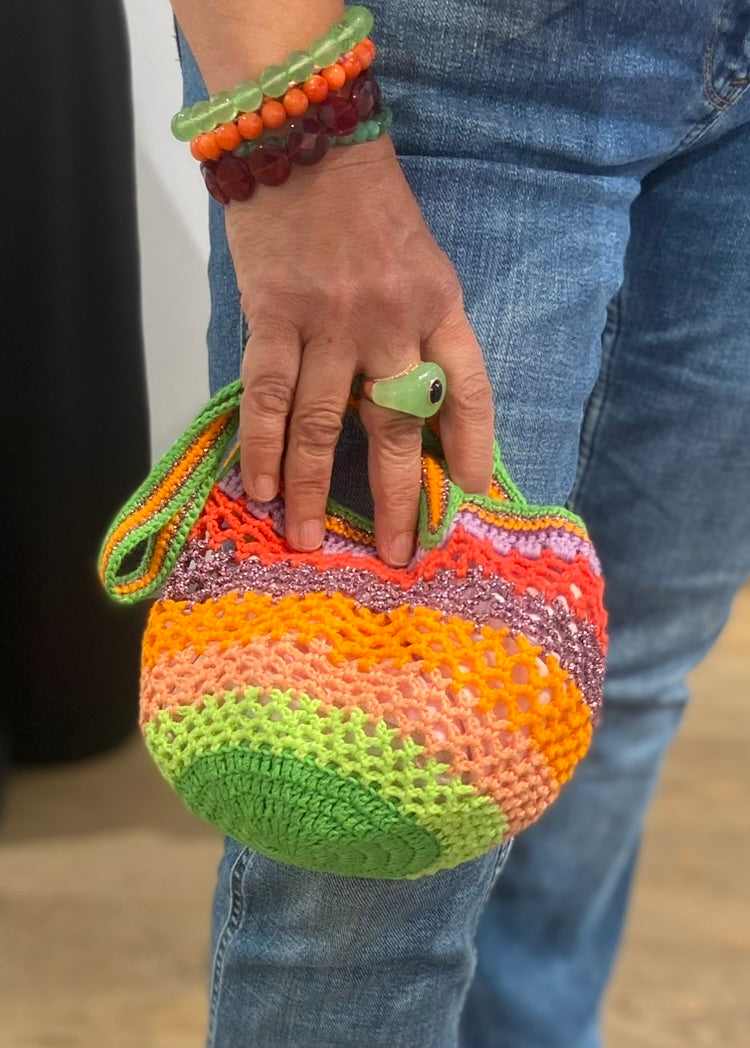 Person holding the Lil Sis Funky handmade crochet bag in neon green, orange, pink and red, designed in Paris by Anabaum
