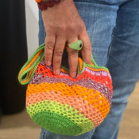Person holding the Lil Sis Funky handmade crochet bag in neon green, orange, pink and red, designed in Paris by Anabaum