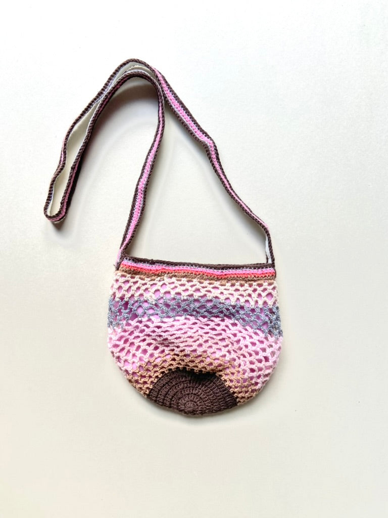 Full view of the Lil Sis Sandstorm crochet shoulder bag on a white background, rounded shape with multicolor pink, mauve and brown striped strap